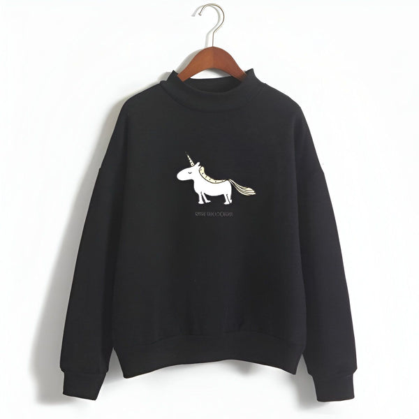 Une image d'un sweat-shirt noir avec une illustration d'une licorne dorée. La licorne est représentée de profil, avec une crinière et une queue dorées. Le sweat-shirt a un col montant et des manches longues.