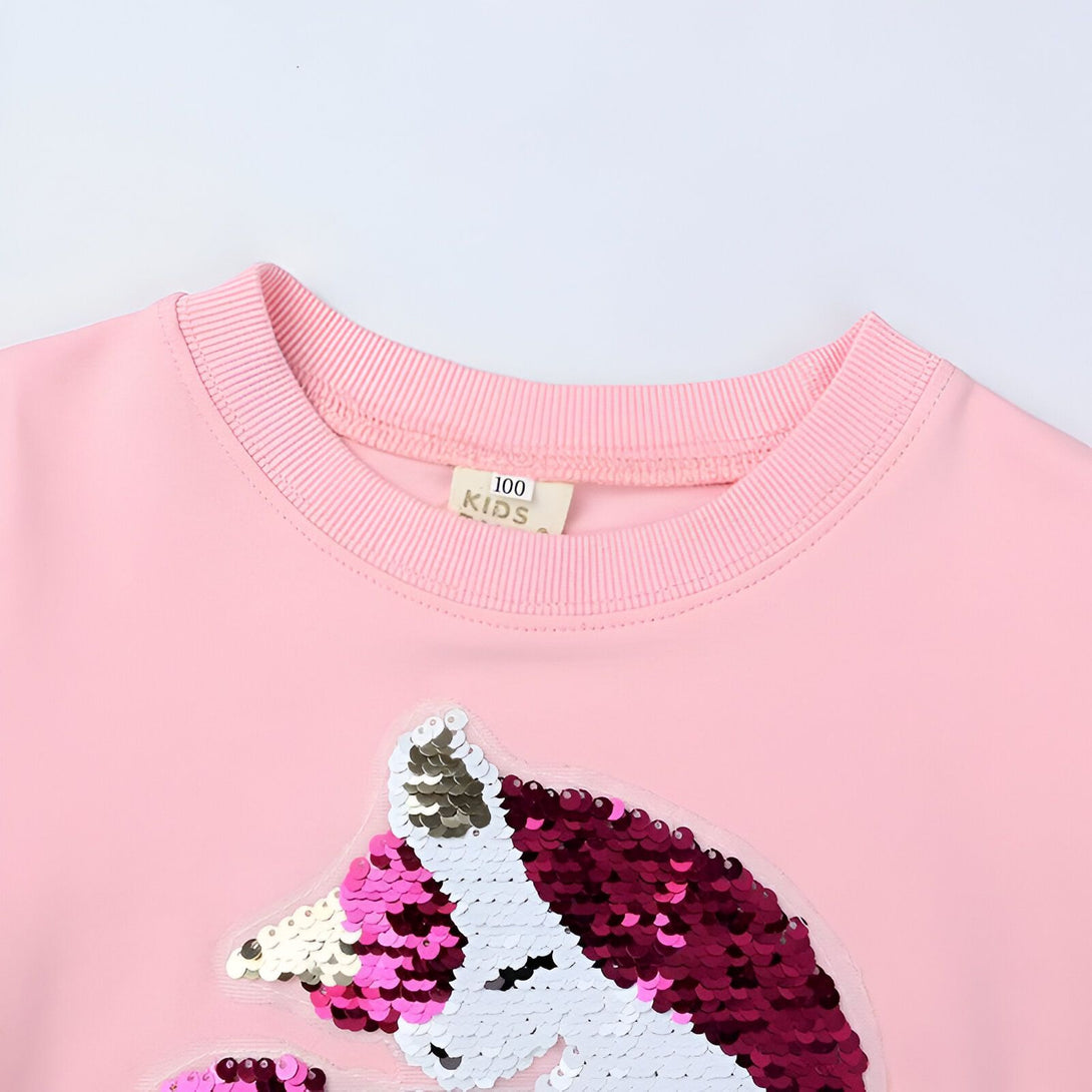 Une image d'un sweat-shirt rose pour enfant avec des paillettes en forme de licorne.