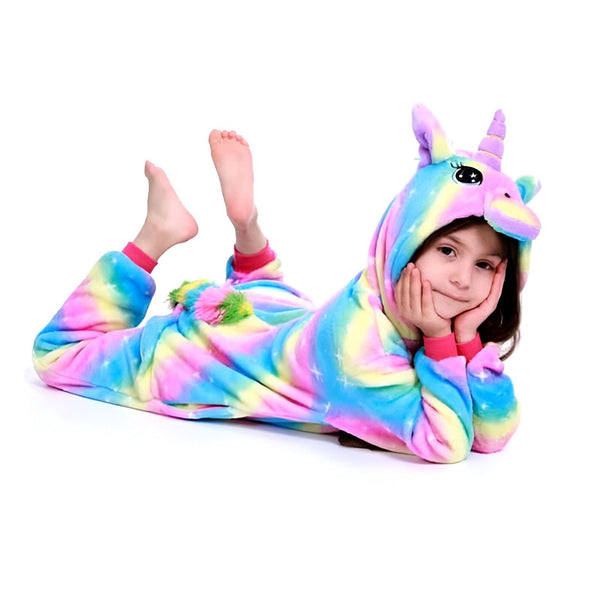 Petite fille souriante portant un pyjama licorne multicolore, allongée sur le ventre avec les mains sous le menton et les pieds en l'air. Déguisement fantaisie et confortable pour enfants., 45502362779903,45502363009279,45502363140351,45502363271423,45502363435263,45502363566335,45502363697407,45502363828479 | Licorne Shop