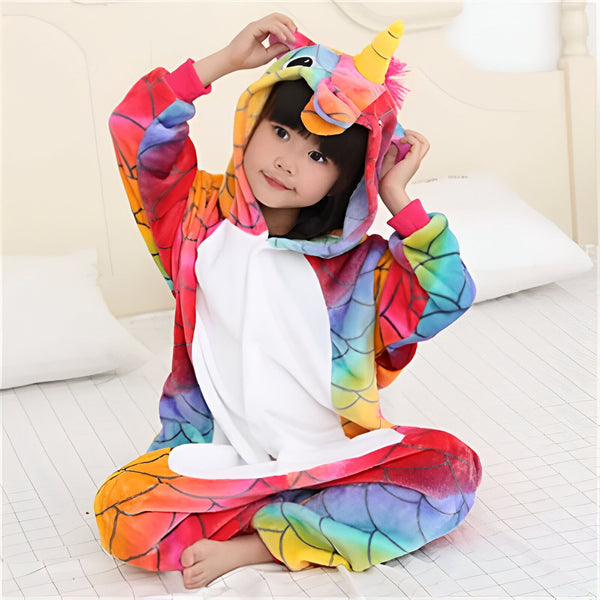 Une fillette portant un pyjama licorne coloré à capuche, assise sur un lit blanc, souriant à la caméra., 45501967007999,45501967040767,45501967073535,45501967106303,45501967171839,45501967302911,45501967433983,45501967499519 | Licorne Shop