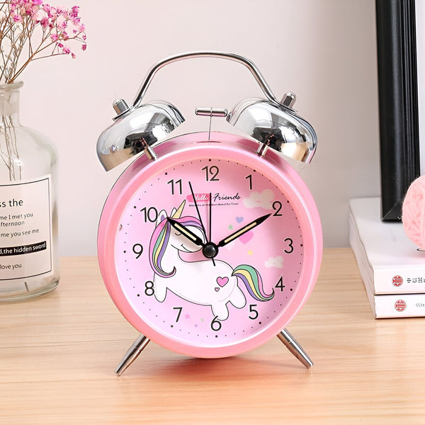 Réveil rose avec un motif de licorne sur le cadran. Fleurs décoratives en arrière-plan, posé sur une table en bois. Cloches métalliques pour le réveil.
, 45501031284991 | Licorne Shop