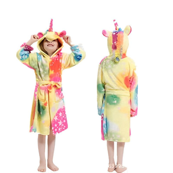 Une petite fille porte une robe de chambre fantaisie licorne à capuche, aux couleurs vives, posant avec les mains près de la capuche, avec une autre robe de chambre licorne floue à l'arrière-plan., 45502041686271,45502041719039,45502041751807,45502041784575,45502041817343,45502041850111,45502041882879,45502041915647 | Licorne Shop