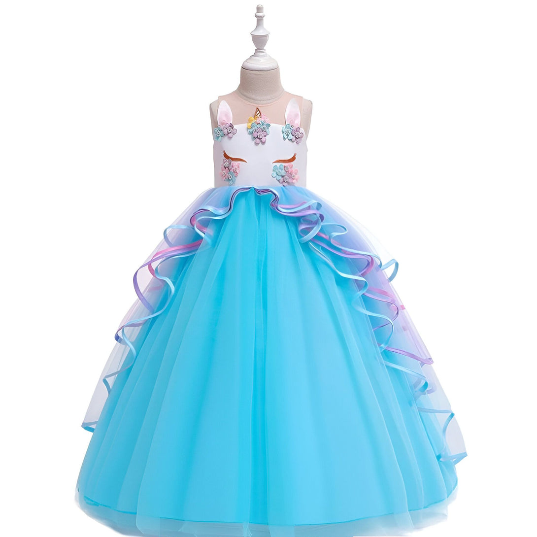 Une robe de soirée bleue à motifs de licorne pour fille. La robe est en tulle et comporte plusieurs couches de volants. Elle est ornée de fleurs et de paillettes.