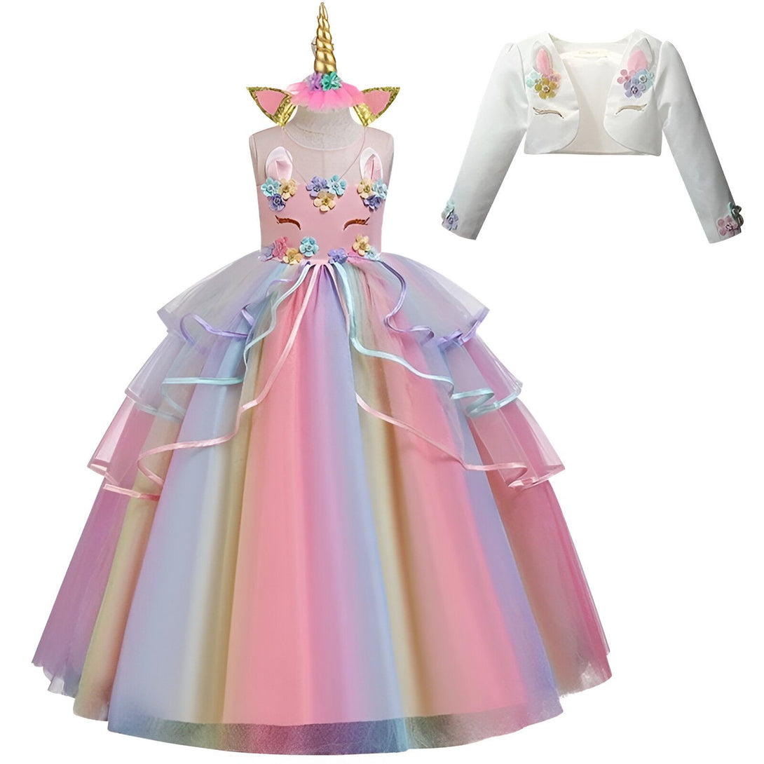 Une robe de princesse licorne arc-en-ciel avec une veste blanche. La robe est faite de tulle et de fleurs en 3D. La veste est en satin avec des manches bouffantes.