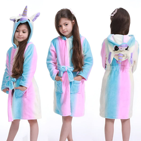 Une petite fille portant un peignoir de bain doux à capuche en forme de licorne, rayé de couleurs pastel rose, bleu et blanc. Vues de face et de dos., 45502350983423,45502351016191,45502351048959,45502351081727,45502351114495,45502351147263,45502351180031,45502351212799 | Licorne Shop