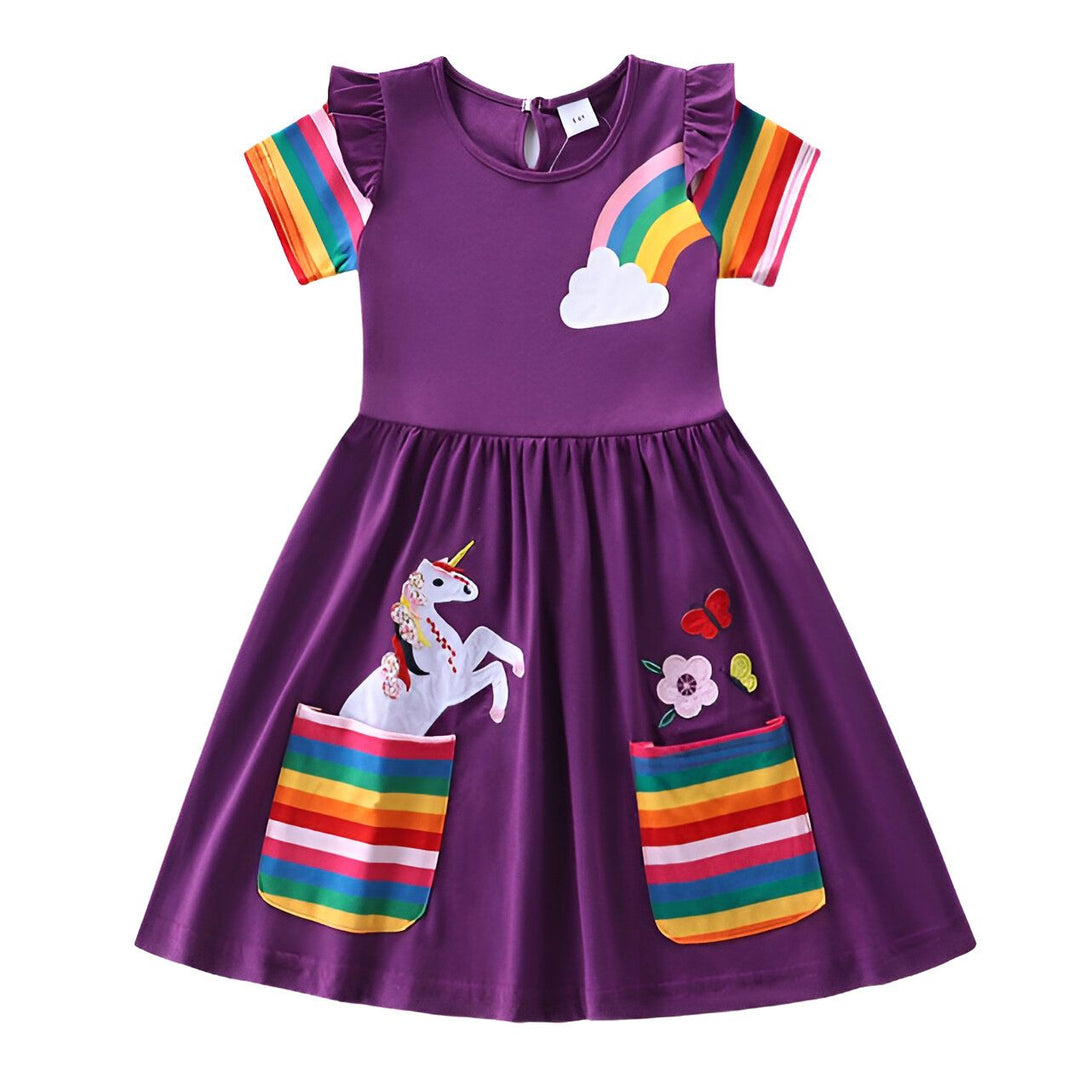 Une robe violette à manches courtes avec une poche arc-en-ciel sur le devant. Sur la robe, il y a une licorne brodée avec des fleurs et un arc-en-ciel.