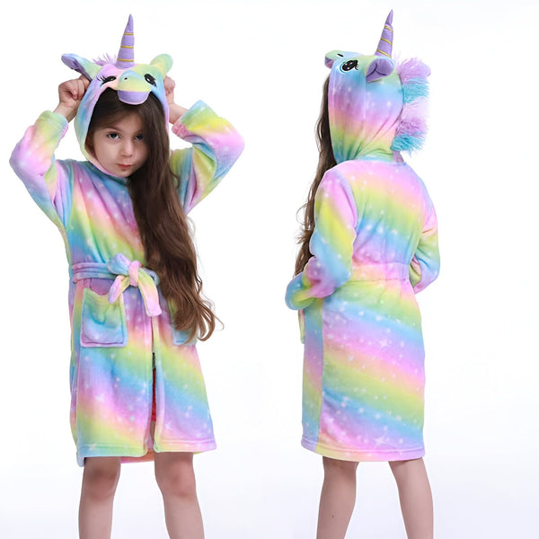 Une fillette vue de face et de dos porte un peignoir doux à capuche licorne avec un motif arc-en-ciel pastel. Le peignoir est ceinturé et a une poche. Elle sourit et met ses mains sur la capuche., 45502343971071,45502344003839,45502344036607,45502344069375,45502344102143,45502344134911,45502344167679,45502344200447 | Licorne Shop