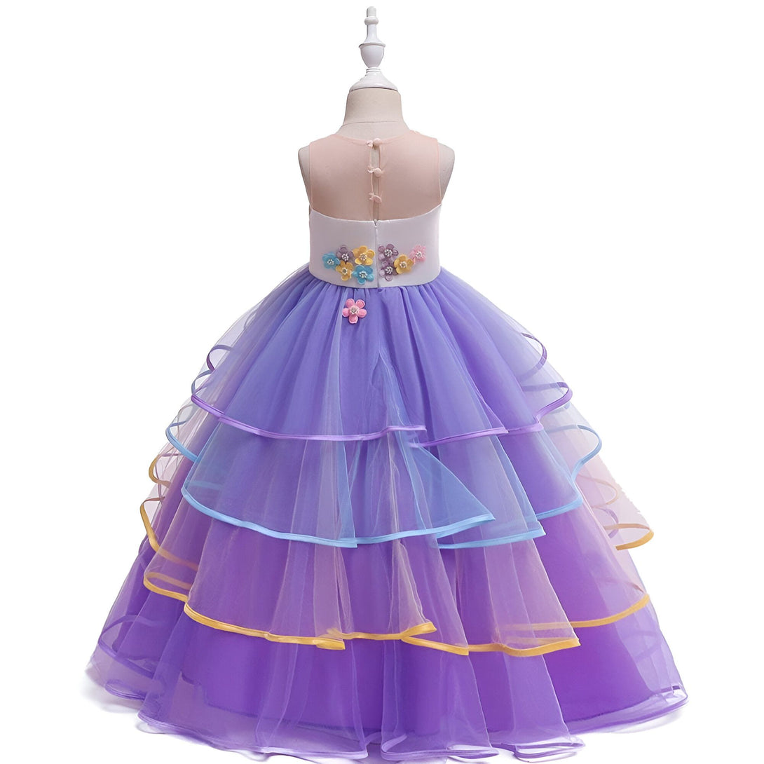 Une robe de soirée licorne pour fille avec un jupon en tulle multicouche et des fleurs en 3D sur le corsage.