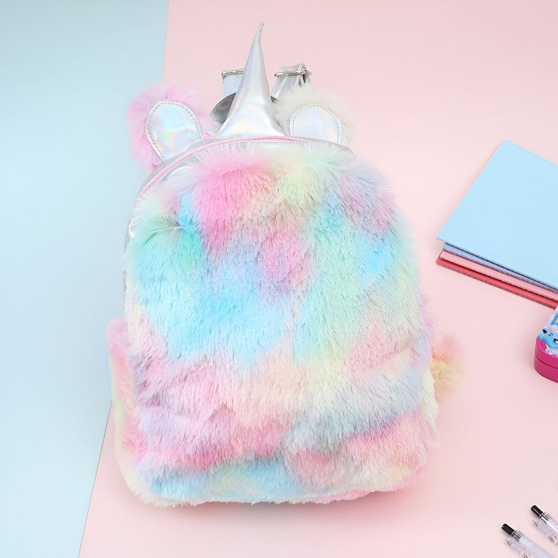 Une peluche de sac à dos de licorne. La peluche est de couleur arc-en-ciel et a une corne et des oreilles de licorne.