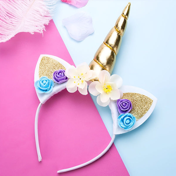 Serre-tête licorne avec corne dorée, oreilles blanches à paillettes dorées et fleurs blanches, bleues et violettes. Fond rose et bleu pastel., 45501336453375 | Licorne Shop