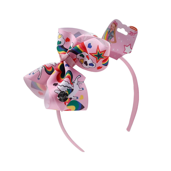 Serre-tête rose pour enfant avec un grand nœud JoJo Siwa. Le nœud est rose et décoré de motifs licornes, arcs-en-ciel, étoiles et cœurs. L'emballage est visible en haut à droite., 45501376168191 | Licorne Shop