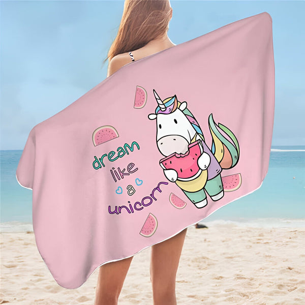 Femme à la plage tenant une serviette rose avec une licorne mangeant une pastèque. L'inscription "dream like a unicorn" est également visible., 45501255418111 | Licorne Shop