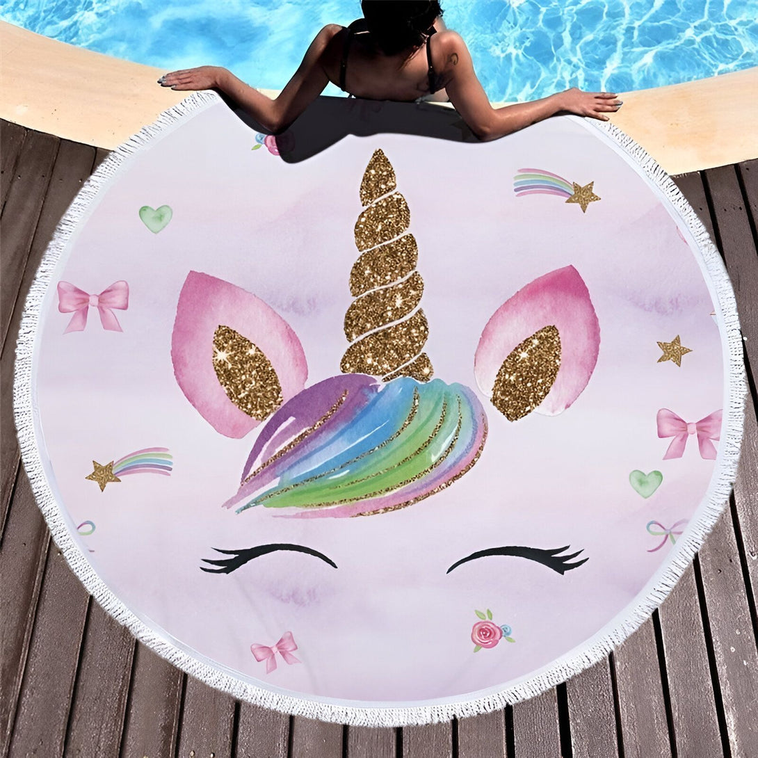 Serviette de plage ronde avec motif licorne rose et doré. Une femme se prélasse au bord de la piscine, la serviette étalée sur le sol en bois. Détails brillants et motifs enfantins., 45501256532223 | Licorne Shop