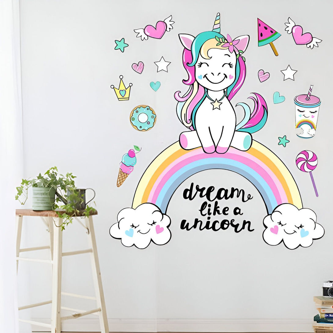 Une illustration d'une licorne assise sur un arc-en-ciel. La licorne est entourée de coeurs, d'étoiles, de nuages, d'un beignet, d'une glace, d'une pastèque et d'un milkshake. Le texte "Dream like a unicorn" est écrit sous la licorne.