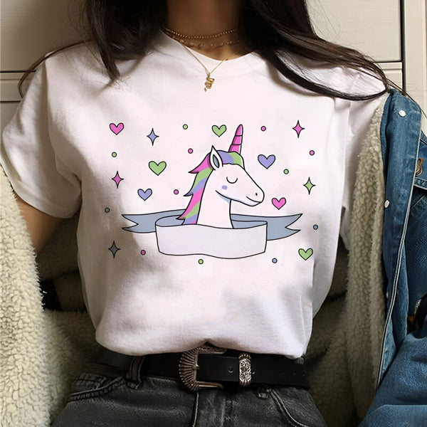 Une jeune femme porte un t-shirt blanc avec un motif de licorne. La licorne a une crinière et une queue arc-en-ciel, et il y a des cœurs et des étoiles autour d'elle. Le t-shirt est rentré dans un jean bleu.