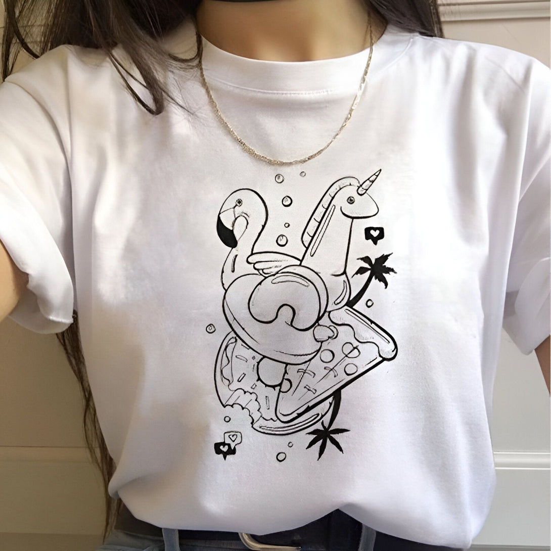 Le dessin représente un t-shirt blanc avec un dessin d'un flamant rose, d'une licorne et d'une pizza. Le flamant rose est assis sur une bouée, la licorne est debout à côté de la bouée et la pizza est posée sur le sol. Il y a aussi des palmiers et des bulles dans le dessin.