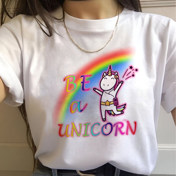 Une image d'une licorne blanche avec une crinière et une queue arc-en-ciel. La licorne porte des écouteurs et danse. Il y a un arc-en-ciel coloré derrière la licorne et le texte "Be a Unicorn" est écrit en lettres colorées sous la licorne.