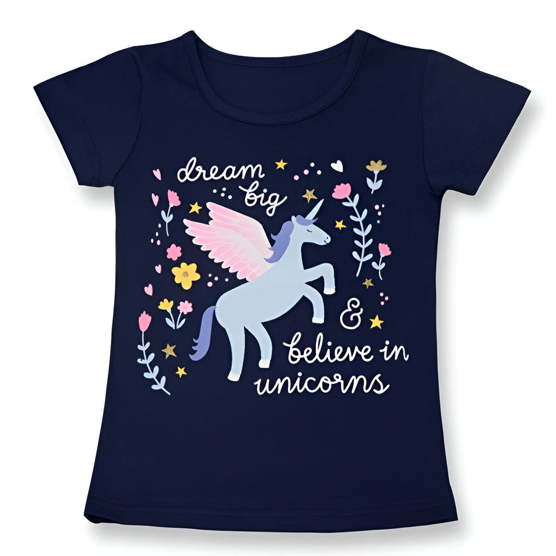 Une illustration d'une licorne ailée avec des fleurs et des étoiles sur un t-shirt bleu marine pour enfant. Le texte sur le t-shirt dit "Dream Big & Believe in Unicorns".