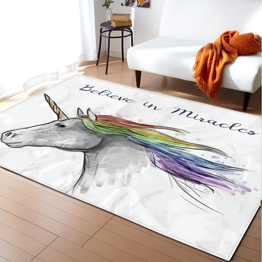 Tapis rectangulaire avec un dessin de licorne aux crins arc-en-ciel et les mots "Believe in Miracles". Le tapis est dans un salon avec un fauteuil et une table basse., 45501050519807 | Licorne Shop