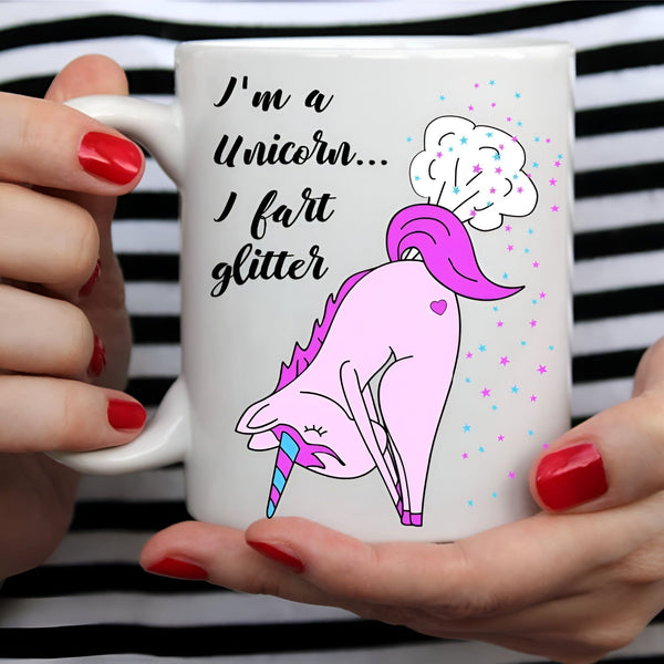 Gros plan d'une tasse à café blanche tenue par des mains aux ongles rouges. La tasse porte un dessin humoristique d'une licorne rose avec la citation « Je suis une licorne... Je pète des paillettes ». Arrière-plan rayé noir et blanc., 45501188636927 | Licorne Shop