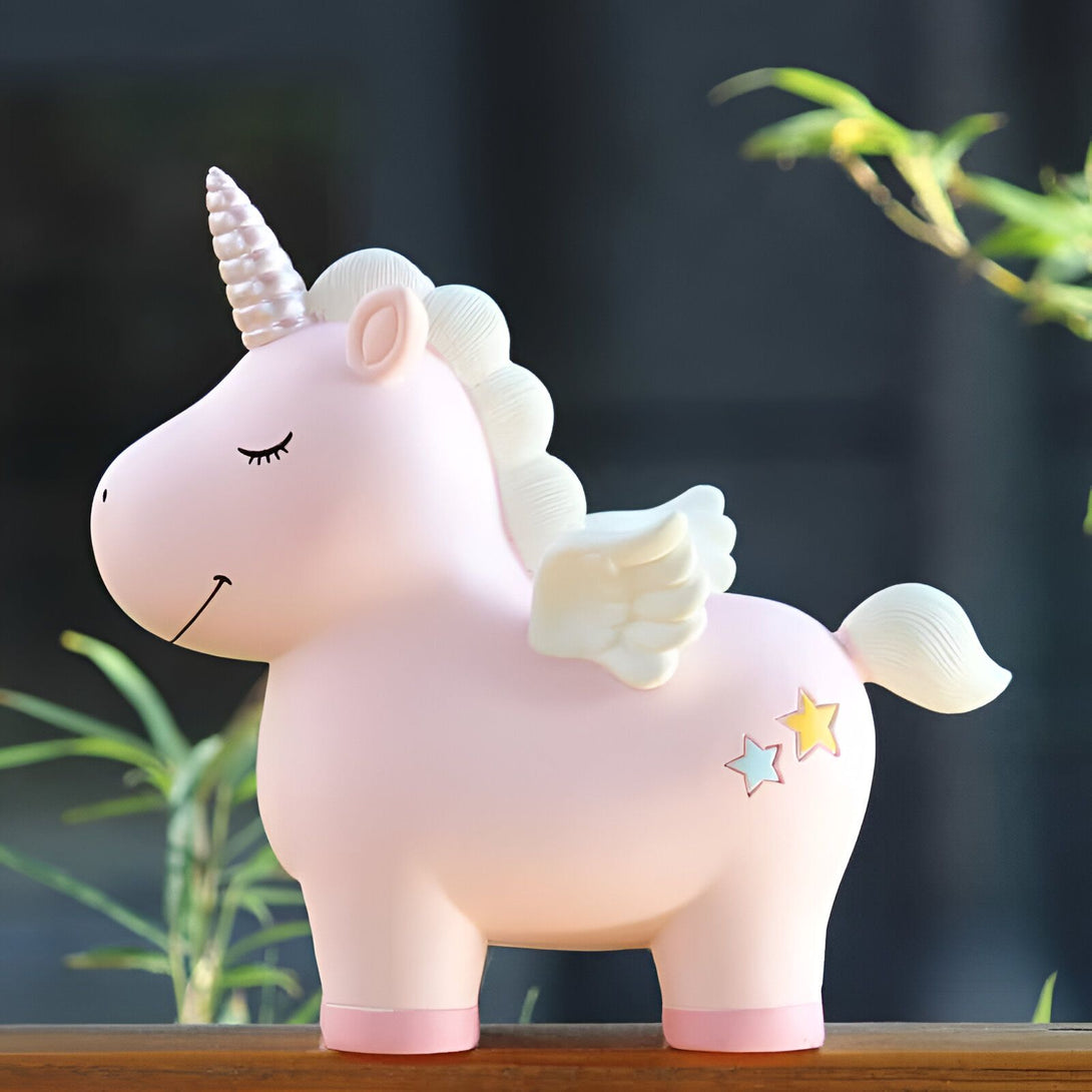 Image d'une tirelire licorne rose avec une crinière blanche, une corne scintillante et des petites ailes blanches. Elle a des étoiles sur son arrière-train. Objet décoratif mignon pour enfants., 45501163503871 | Licorne Shop