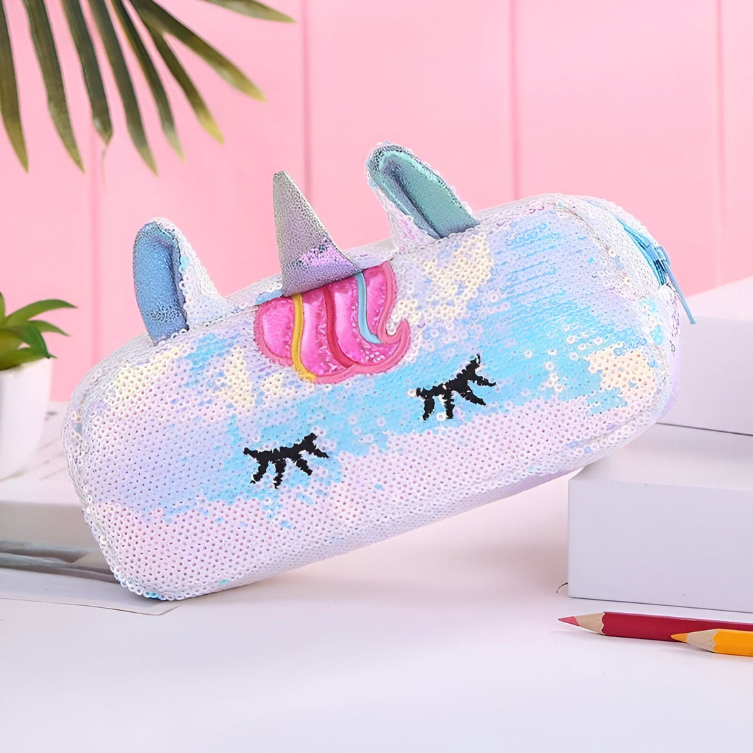 Une trousse scolaire en forme de licorne blanche avec des paillettes réversibles. La trousse est ouverte et on peut voir l'intérieur en tissu rose.