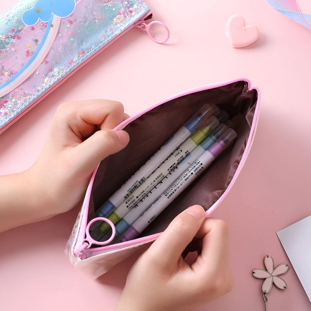 Une trousse transparente avec des paillettes et un motif arc-en-ciel. La trousse est ouverte et on peut voir des stylos et des marqueurs à l'intérieur.