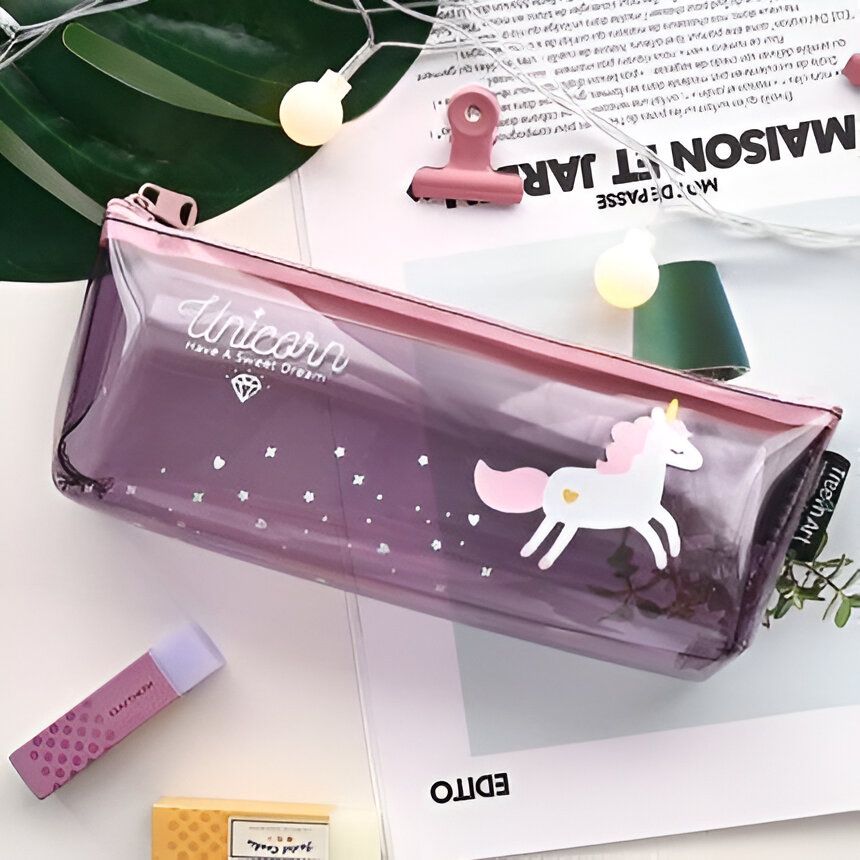 Une trousse transparente avec une licorne imprimée dessus. La trousse est remplie de fournitures scolaires, dont des crayons, des stylos et une gomme.