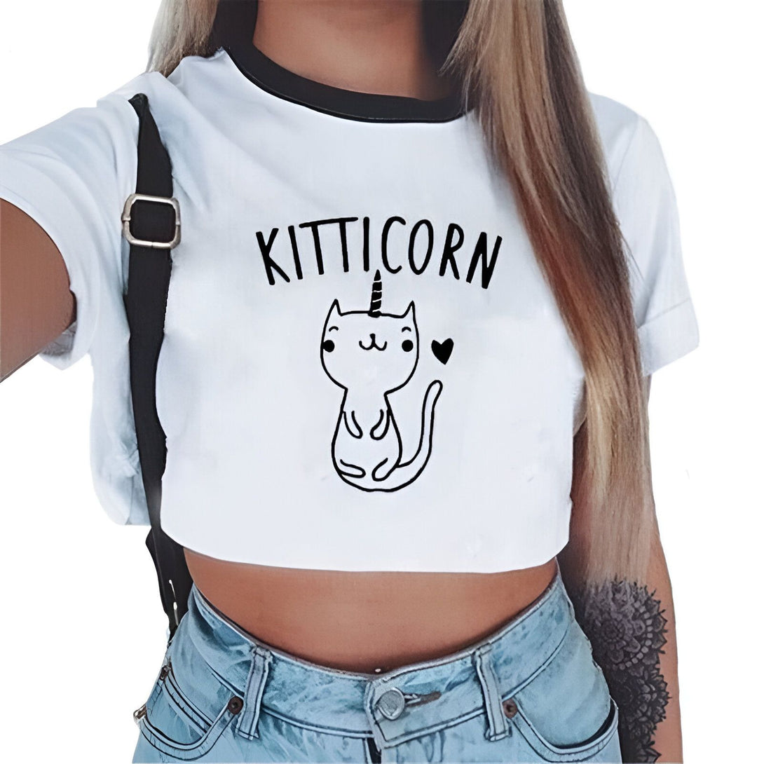 Femme portant un crop top blanc avec un chat-licorne dessiné et le mot "kitticorn", jean taille basse, sac à bandoulière noir., 45501297033471 | Licorne Shop