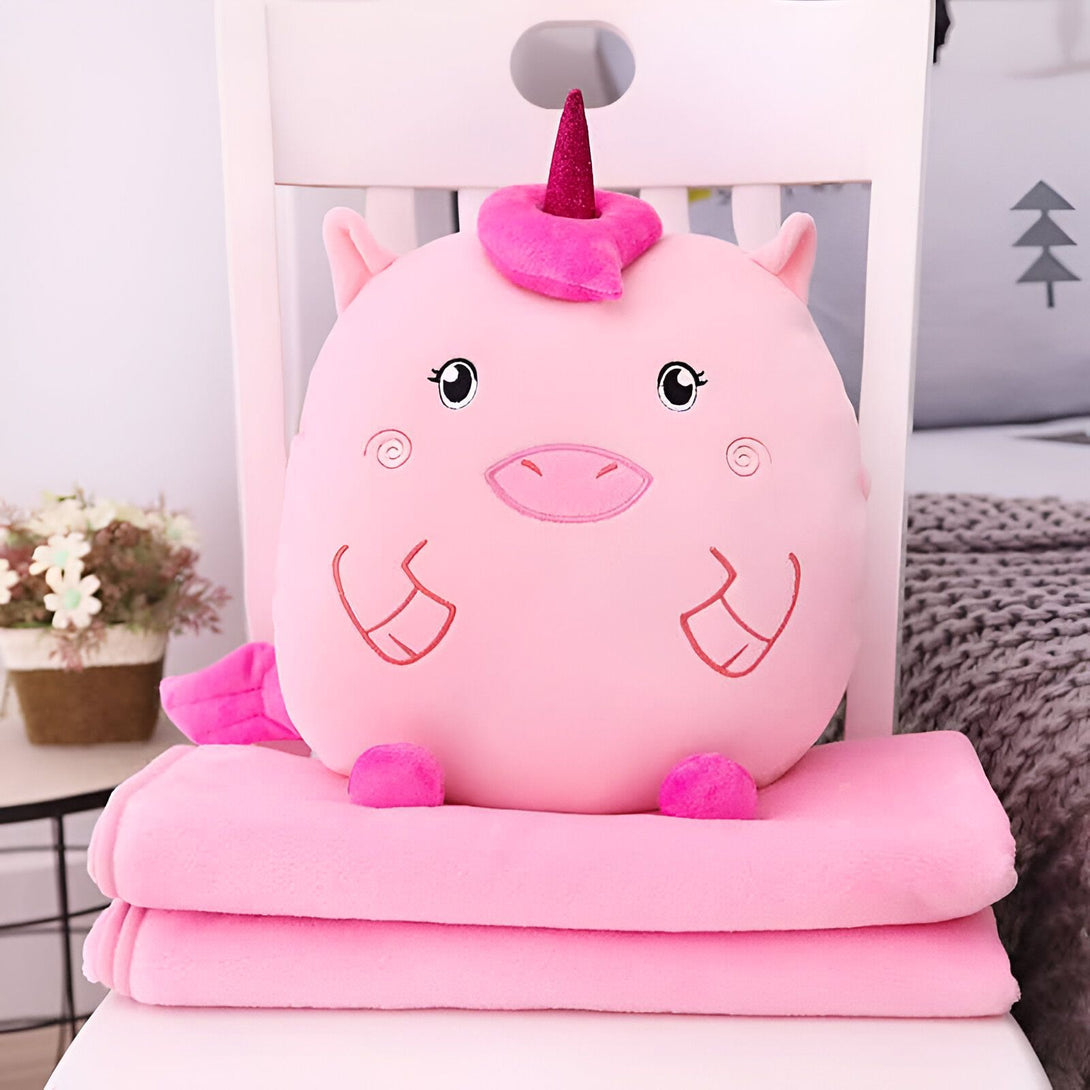 Coussin doux en forme de licorne rose avec une couverture assortie, posé sur une chaise blanche. Cadeau idéal pour enfants ou décoration de chambre. Confort et douceur garantis., 45501421715711 | Licorne Shop