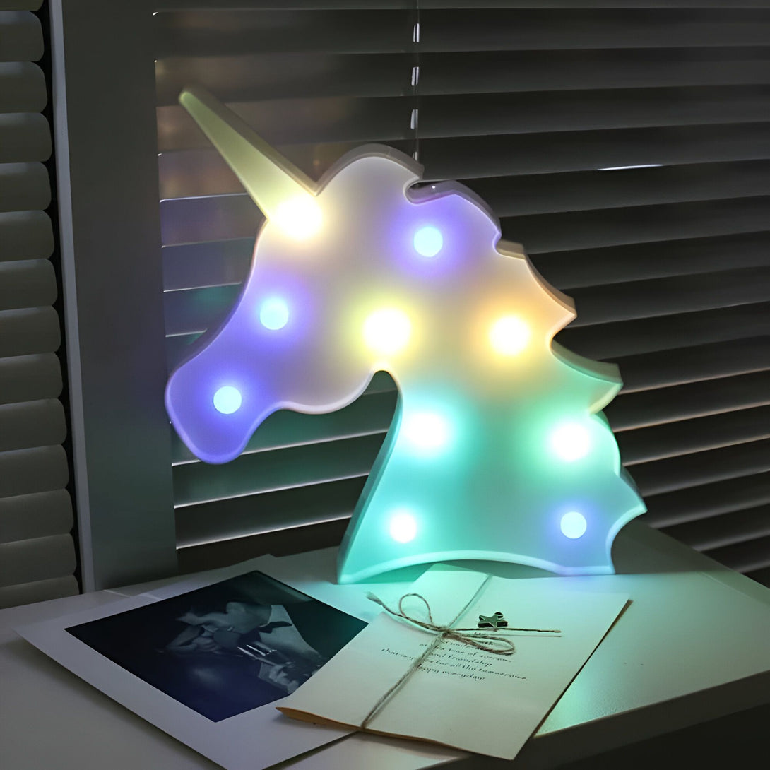 Lampe décorative licorne illuminée, posée sur une table avec une photo et une lettre. Lumière douce, ambiance féerique, décoration intérieure., 45501048455423 | Licorne Shop