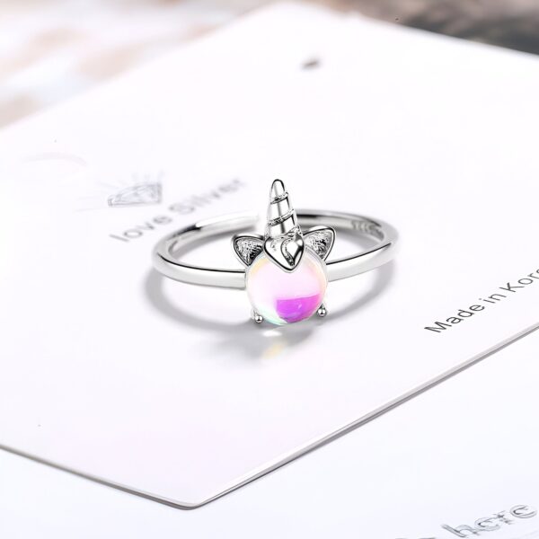 Une bague en argent avec une pierre précieuse opale blanche et rose en forme de licorne.