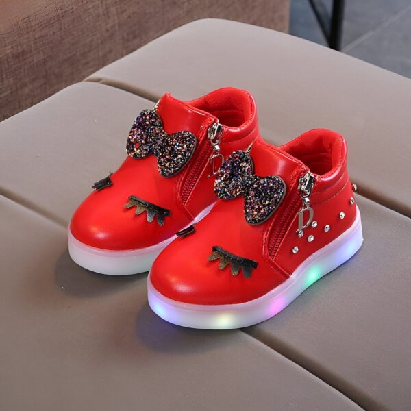 Une paire de chaussures rouges pour enfant avec des nœuds pailletés et des lumières LED dans les semelles.
