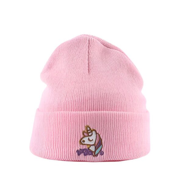 Une image d'un bonnet rose avec une licorne brodée dessus. La licorne est blanche avec une crinière et une queue violettes. Le bonnet est porté par un enfant.