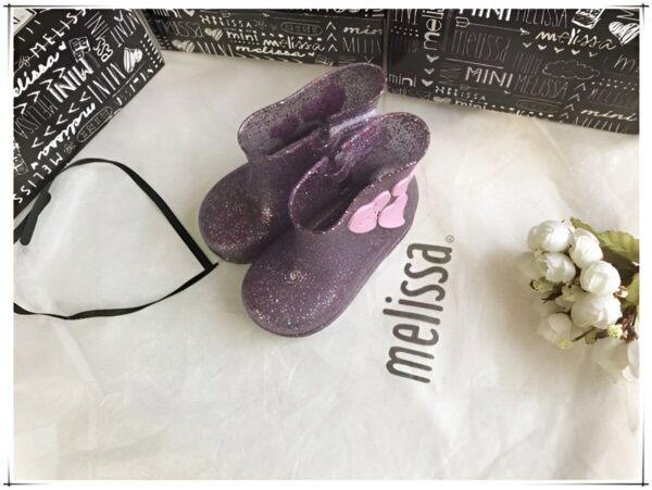 bottes-licorne-impermeables-en-forme-de-coeur-1a-1.jpg Bottes de pluie violettes à paillettes Mini Melissa sur sac en tissu blanc avec logo Melissa, emballage et fleurs blanches. Chaussures pour enfant tendance et mignonnes., 45501102358783,45501102391551,45501102424319,45501102457087,45501102489855,45501102522623,45501102555391,45501102588159,45501102620927 | Licorne Shop