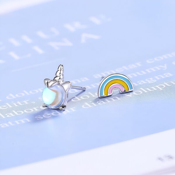 boucles-d-oreilles-licorne-arc-en-ciel-kawaii-2a.jpg Une image de deux boucles d'oreilles en forme de licorne et d'arc-en-ciel. Les boucles d'oreilles sont en argent et ont une pierre précieuse opalescente. L'arc-en-ciel est coloré et a des couleurs vives.