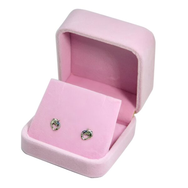 boucles-d-oreilles-licorne-diamant-argent-1a.jpg Une paire de boucles d'oreilles en forme de licorne en argent avec des pierres bleues dans une boîte à bijoux en velours rose.