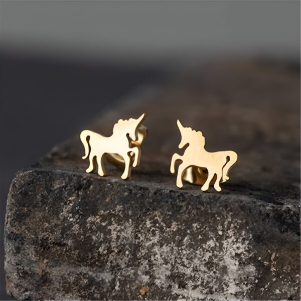 boucles-d-oreilles-licorne-en-or-blanc-diamant-et-emeraude-1a.jpg Paire de boucles d'oreilles en forme de licorne dorée, posées sur une pierre. Bijoux fantaisie, cadeau pour femme ou enfant, symbole de magie et de féérie. Accessoires de mode originaux., 45501712761087 | Licorne Shop