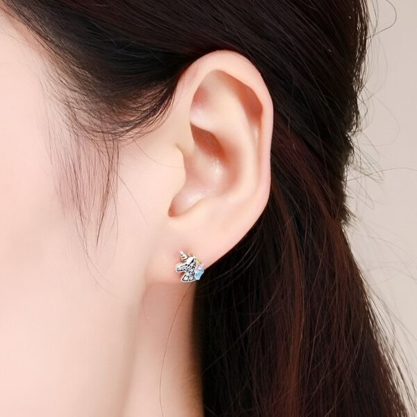 boucles-d-oreilles-licorne-fantaisie-argent-1a.jpg Une image d'une boucle d'oreille en forme de licorne. La licorne est blanche avec une crinière et une queue roses. La boucle d'oreille est en argent.
