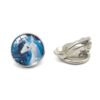 boucles-d-oreilles-licorne-femme-elegante-clip-1a-1.jpg Une paire de boucles d'oreilles en forme de licorne blanche avec une crinière et une queue bleues. Les boucles d'oreilles sont en métal argenté et ont une forme ronde. L'image de la licorne est entourée d'un cercle bleu foncé.