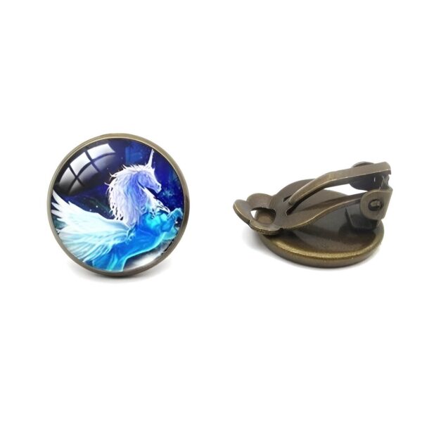 boucles-d-oreilles-licorne-fille-bleu-clip-2a.jpg Une paire de boucles d'oreilles en bronze avec un cabochon en verre rond représentant une licorne ailée blanche et bleue.