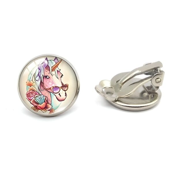 boucles-d-oreilles-licorne-fille-tropical-clip-1a-1.jpg Une paire de boucles d'oreilles en forme de licorne avec des lunettes de soleil. Les licornes sont blanches et ont une crinière et une queue roses. Elles portent des lunettes de soleil noires. Les boucles d'oreilles sont en métal argenté.