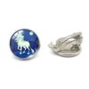 boucles-d-oreilles-licorne-lune-clip-1a.jpg Une paire de boucles d'oreilles en forme de clip avec une image d'une licorne blanche sur un fond bleu nuit. La licorne est représentée avec une crinière et une queue blanches, et elle est entourée d'arbres et de montagnes. Les boucles d'oreilles sont en métal argenté et ont une forme ronde.