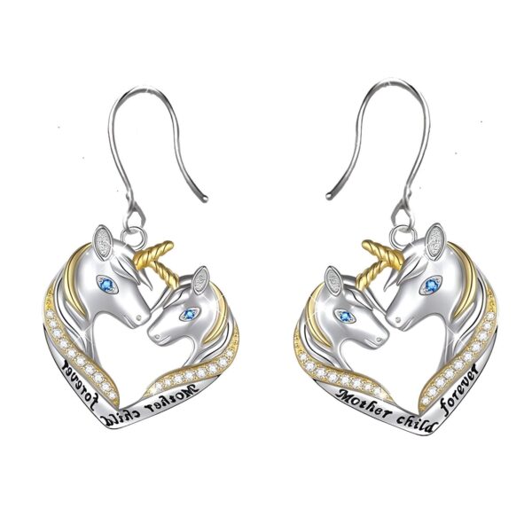 boucles-d-oreilles-licorne-mere-et-fille-pendante-1a.jpg Une paire de boucles d'oreilles en forme de cœur avec deux licornes, une grande et une petite. La grande licorne a une crinière et une queue dorées, et la petite licorne a une crinière et une queue argentées. Les deux licornes ont des yeux bleus. Le cœur est en argent et est décoré de zircons cubiques. Les boucles d'oreilles sont en argent sterling 925 et sont hypoallergéniques.