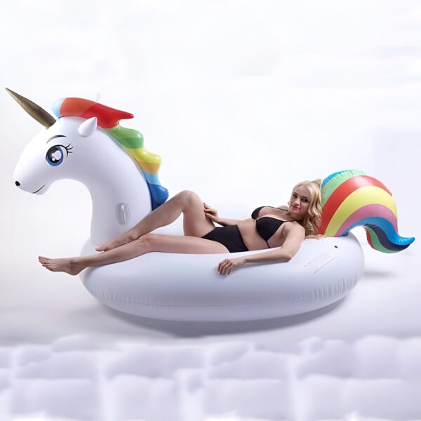 Femme en maillot de bain noir se détendant sur une bouée licorne gonflable blanche avec une crinière et une queue arc-en-ciel. Style de vie estival, amusement à la piscine, détente et insouciance., 45501243949311 | Licorne Shop