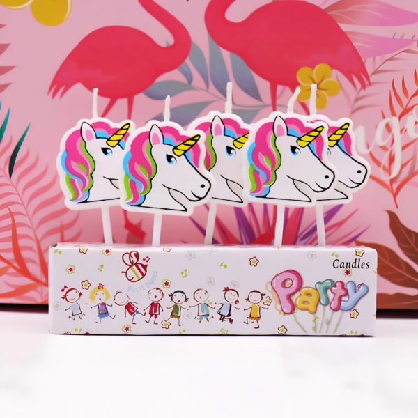 Bougies d'anniversaire décoratives en forme de têtes de licorne colorées. Elles sont présentées dans une boîte avec des motifs enfantins et le mot "Party". En arrière-plan, un papier cadeau rose avec des flamants roses., 45501141188863 | Licorne Shop