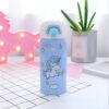bouteille-d-eau-550-ml-licorne-mignonne-pour-enfant-1a.jpg Gourde isotherme bleu clair décorée d'un motif de licorne blanche et d'éléments célestes (étoiles, nuages, arc-en-ciel). En arrière-plan, décoration en forme de licorne lumineuse rose et plante verte en pot., 45501178118399 | Licorne Shop