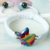 Un bracelet en corde blanche avec un pendentif licorne arc-en-ciel. La licorne a une crinière et une queue arc-en-ciel, et un visage souriant. Le bracelet est ajustable et convient à la plupart des tailles de poignet.