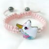Un bracelet rose avec un pendentif licorne en émail. La licorne est blanche avec une crinière et une queue arc-en-ciel.