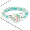 bracelet-licorne-a-perles-bleues-et-blanches-avec-pendentif-1a.jpg Bracelet de perles turquoise avec un pendentif rond argenté orné d'une illustration d'une licorne aux cheveux roses entourée de fleurs et de coeurs. Bijou fantaisie pour enfant., 45501396615423 | Licorne Shop
